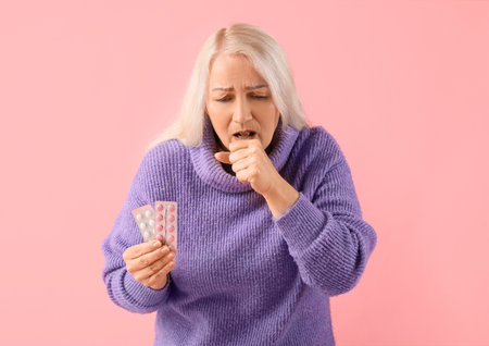 Sick mature woman with pills on pink backgroundの写真素材