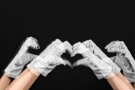 Stroboscopic photo of moving woman in gloves making heart gesture on dark backgroundの写真素材