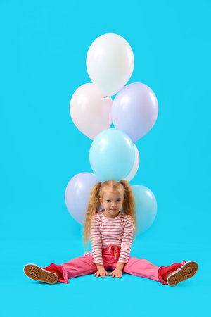 Cute little girl with beautiful balloons sitting on blue backgroundの写真素材