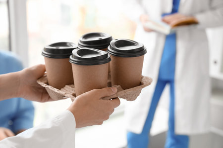 Young doctor with cups of coffee in clinic, closeupの写真素材