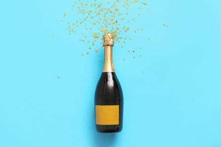 Bottle of champagne and confetti on blue backgroundの写真素材