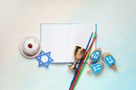 Hanukkah composition with open book, donut, candles and dreidels on light blue backgroundの写真素材