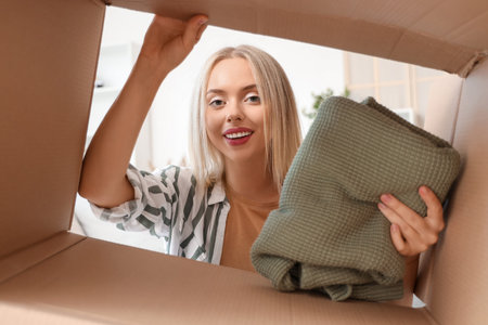 Young woman putting folded sweater in box, view from inside