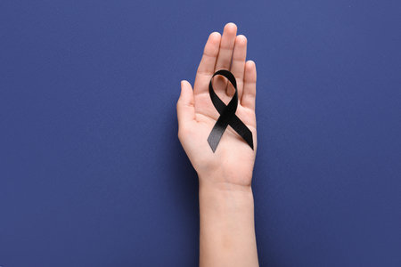 Woman holding black funeral ribbon on blue backgroundの写真素材