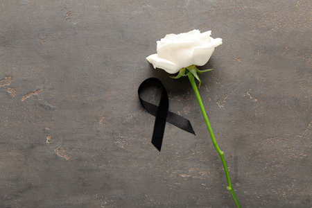 Beautiful rose flower with black funeral ribbon on gray backgroundの写真素材
