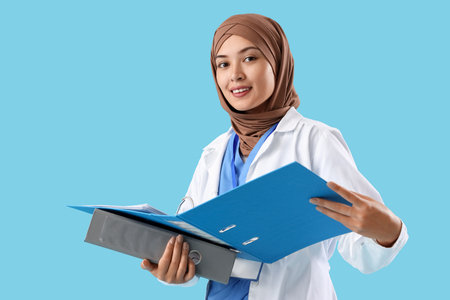 Female Muslim doctor with folders on blue backgroundの写真素材