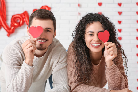 Young couple with paper hearts for Valentine's day at homeの写真素材