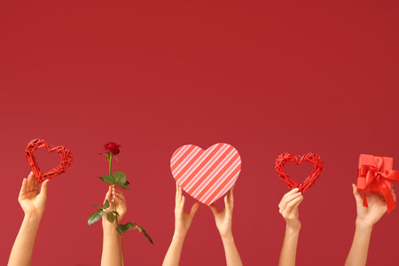 Female hands with decorative hearts, red rose and gift boxes on color background. Valentine's Day celebrationの写真素材