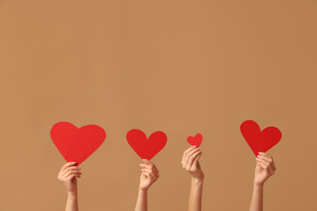 Female hands with red paper hearts on brown background. Valentine's Day celebrationの写真素材