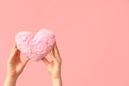 Female hands with fabric heart on pink background. Valentine's Day celebrationの写真素材
