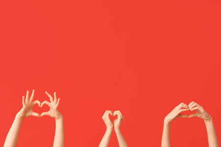 Female hands showing heart gesture on red background. Valentine's Day celebrationの写真素材