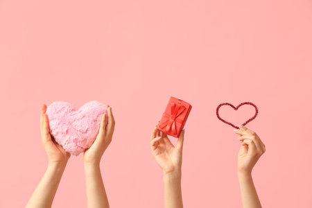 Female hands with fabric heart and gift box on pink background. Valentine's Day celebrationの写真素材