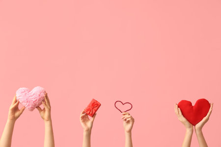 Female hands with fabric hearts and gift box on pink background. Valentine's Day celebrationの写真素材