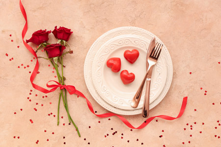 Beautiful table setting with red roses, hearts and confetti on beige background. Valentine's Day celebrationの写真素材