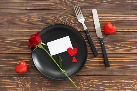 Blank card and beautiful table setting with red rose on wooden background. Valentine's Day celebrationの写真素材
