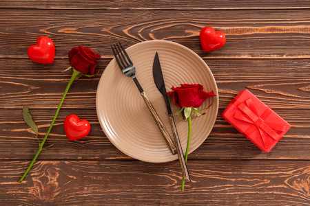 Beautiful table setting with red roses, gift box and hearts on wooden background. Valentine's Day celebrationの写真素材