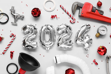 Composition with figure 2024 made of balloons, plumber's items and Christmas decorations on light...