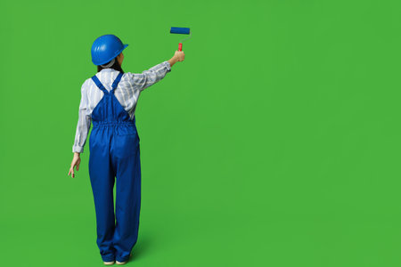 Female Asian painter with roller on green background, back viewの写真素材