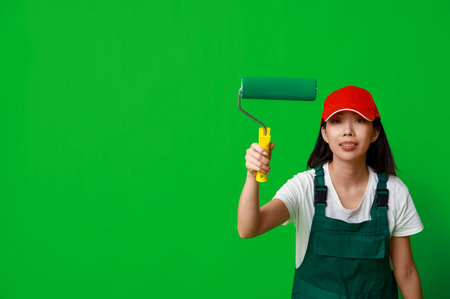 Female Asian painter with roller on green backgroundの写真素材