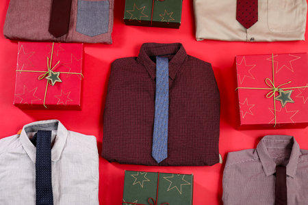 Composition with stylish shirts, neckties and Christmas gifts on red backgroundの写真素材