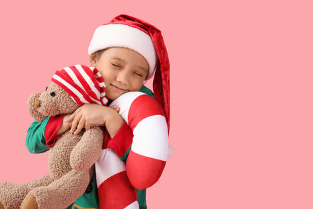 Cute little girl with teddy bear and Christmas cushion on pink backgroundの写真素材