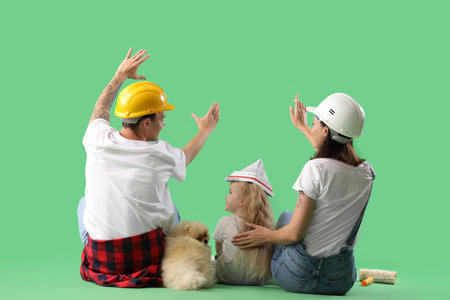 Happy family planning renovation of their new house on green background, back viewの写真素材