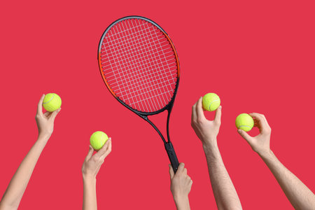 Female hands with racket and tennis balls on red backgroundの写真素材