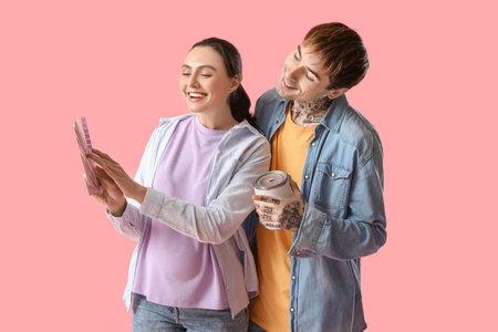 Young pregnant couple with paint can and color palettes on pink backgroundの写真素材