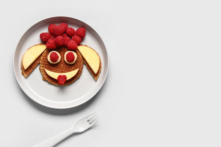 Plate with creative children's breakfast in the shape of funny face on white backgroundの写真素材