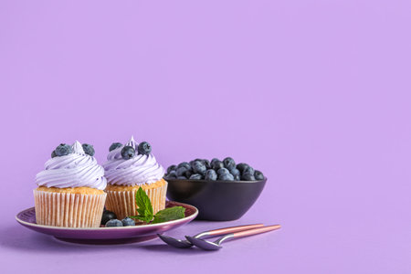 Plate of tasty cupcakes with blueberries on lilac backgroundの写真素材