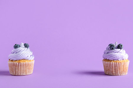 Tasty cupcakes with blueberries on lilac backgroundの写真素材