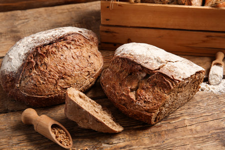 Loaf of fresh rye bread with wheat grains on wooden backgroundの写真素材