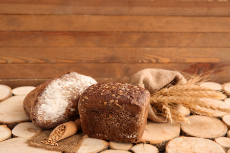 Loaves of fresh bread with wheat spikelets and grains on wooden backgroundの写真素材