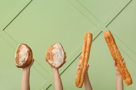 Female hands holding loaves of different fresh bread on green background