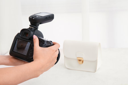 Female photographer taking photo of fashionable purse in studioの写真素材