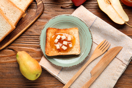 Plate with tasty pear jam and bread on wooden backgroundの写真素材