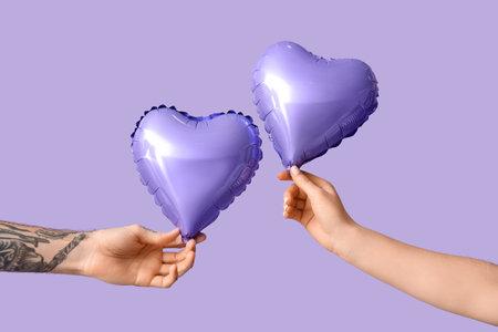 Man and woman with air balloons in shape of heart on lilac background. Valentine's Day celebrationの写真素材
