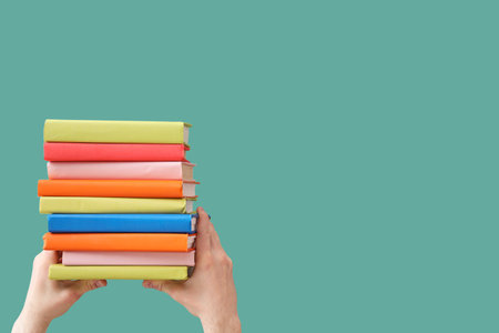 Hands holding books on green backgroundの写真素材