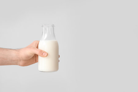Hand with bottle of milk on gray backgroundの写真素材