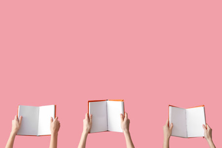 Hands holding open books on pink backgroundの写真素材