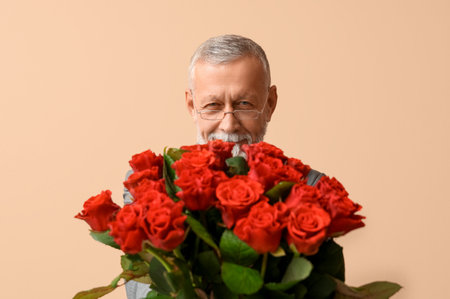 Mature man with bouquet of roses for Valentine's day on beige backgroundの写真素材