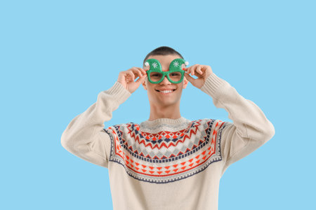 Teenage boy in Christmas eyeglasses on blue backgroundの写真素材