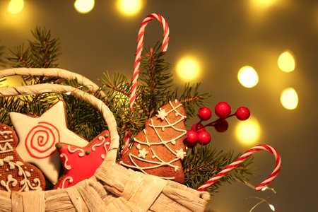 Basket with gingerbread cookies, fir branches and decor against blurred lights. Christmas compositionの写真素材
