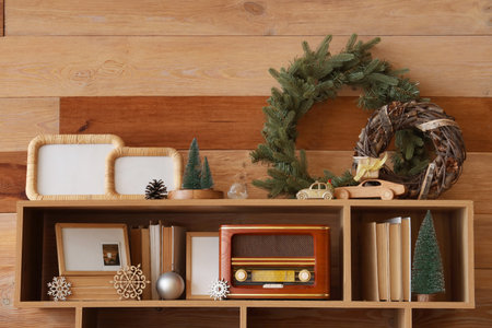 Shelving unit with vintage radio, books and Christmas decorations near wooden wallの写真素材