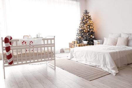 Interior of light bedroom with baby crib and Christmas treeの写真素材