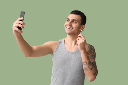 Handsome young man with razor taking selfie on green backgroundの写真素材