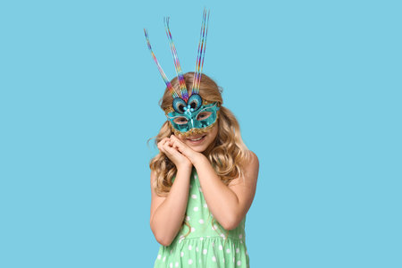 Pretty little girl wearing carnival mask on blue backgroundの写真素材