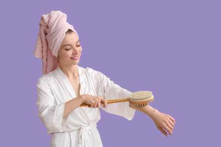 Beautiful woman in gown massaging arm on lilac backgroundの写真素材