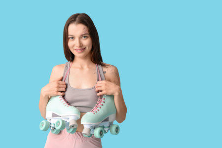 Sporty young woman with roller skates on blue background