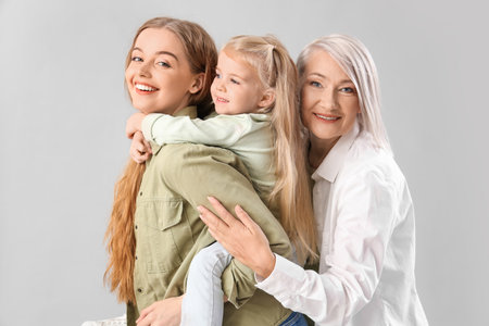 Little girl with her mom and grandmother on light backgroundの写真素材